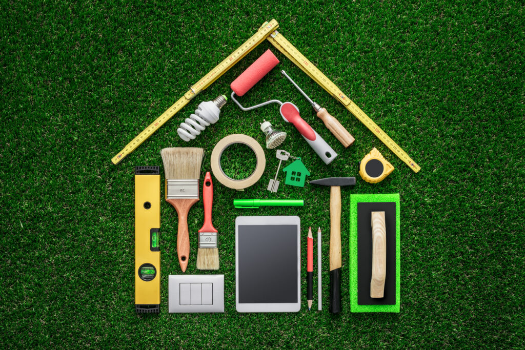 Concept de rénovation de maison, de remodelage et de bricolage, outils de travail et tablette composant une forme de maison sur l'herbe